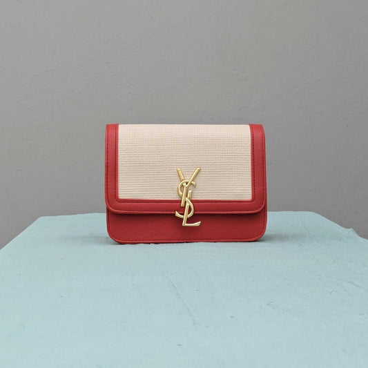 Luxurious crossbody bag with a cream woven-look canvas, red faux leather trim, gold-tone hardware, and an iconic YSL logo. Features an adjustable strap and magnetic closure—perfect for any occasion.